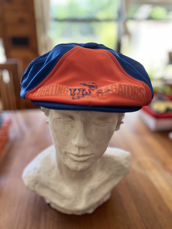 Blue and orange Fighting Gators newsboy cap on display bust, front