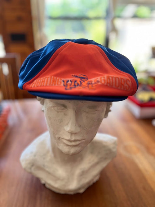 Blue and orange Fighting Gators newsboy cap on display bust, front