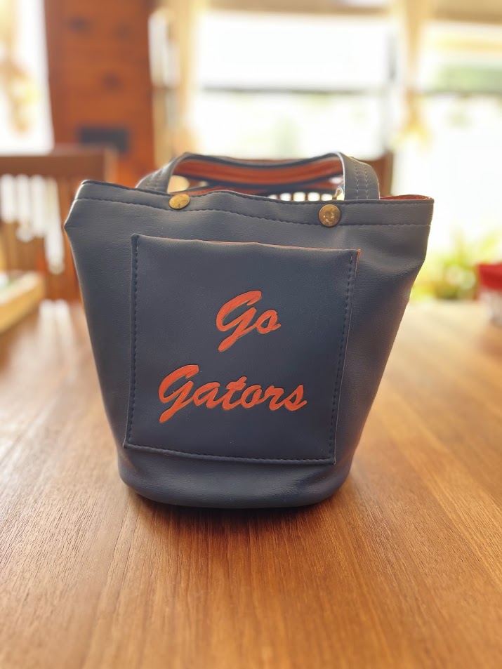 Back of blue vinyl Gators purse with Go Gators script on pocket